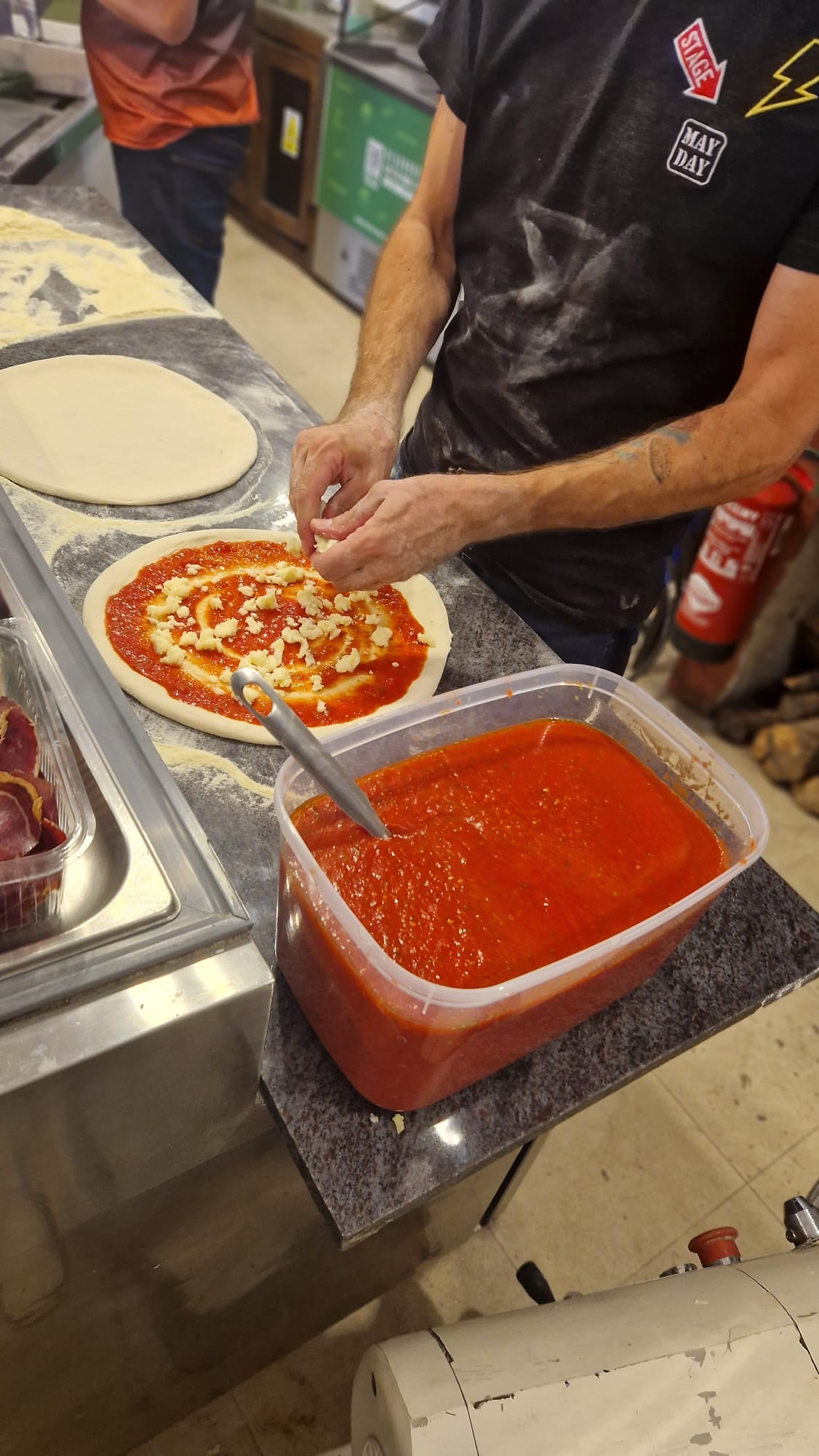Fresh pizza dough being prepared with tomato sauce at La Fondita